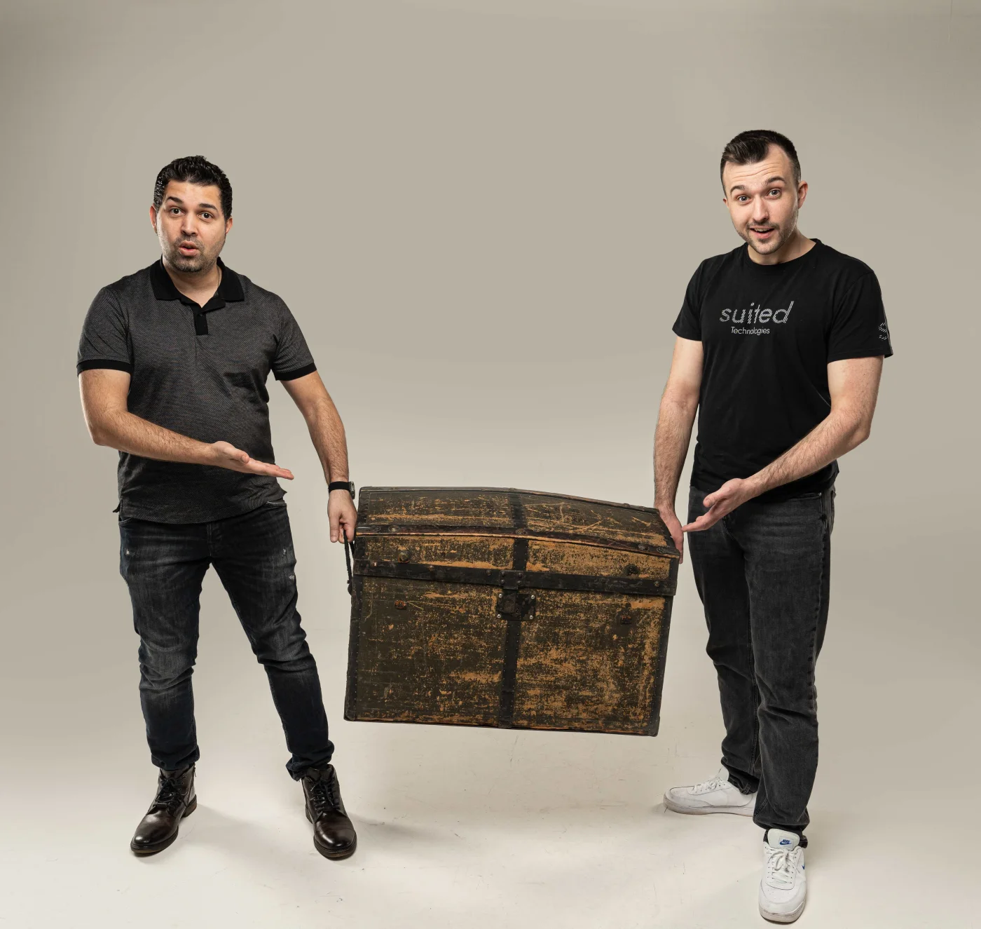 Suited Technologies team members presenting vintage wooden chest